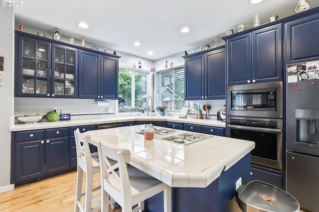 1393 NE 11th Ave, Canby, OR 97013 - kitchen featuring appliances with stainless steel finishes, blue cabinets, light wood-type flooring, glass insert cabinets, and recessed lighting