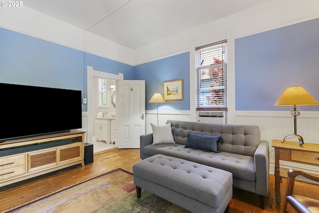 living area featuring wood-type flooring and a wainscoted wall