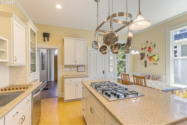 kitchen with stainless steel appliances, plenty of natural light, white cabinets, tasteful backsplash, and ornamental molding
