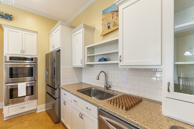 kitchen with a sink, appliances with stainless steel finishes, tasteful backsplash, light stone counters, and white cabinets