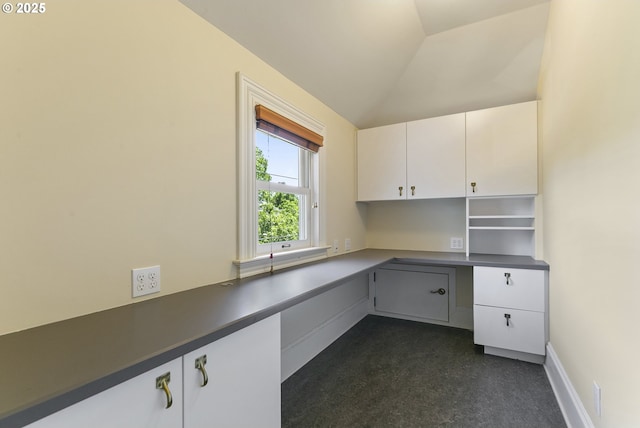 unfurnished office with built in desk and vaulted ceiling