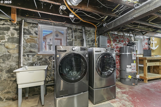 washroom featuring strapped water heater and washer and dryer