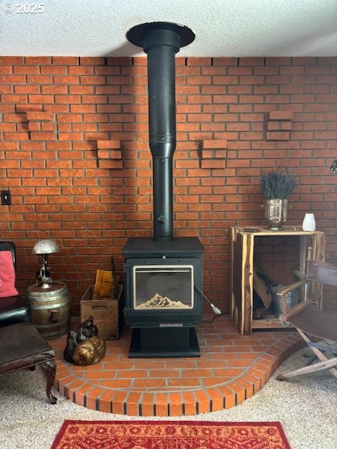 610 SE Maple St, Oakland, OR 97462 - detailed view of a textured ceiling, a wood stove, carpet, and brick wall