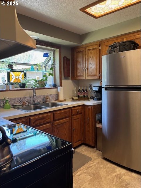 610 SE Maple St, Oakland, OR 97462 - kitchen featuring freestanding refrigerator, a sink, electric range, light countertops, and brown cabinets