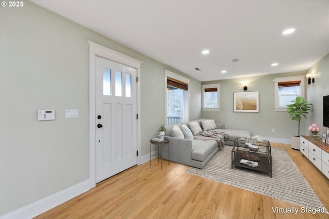 living room with light wood finished floors, recessed lighting, baseboards, and a wealth of natural light