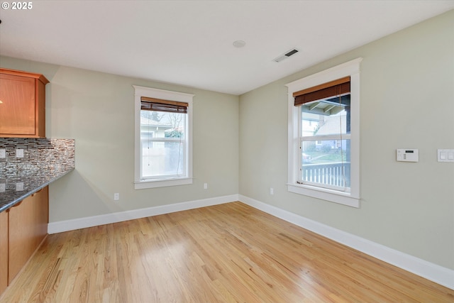 unfurnished dining area featuring visible vents, light wood-type flooring, and baseboards