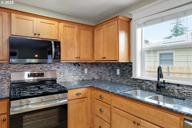 kitchen featuring a sink, decorative backsplash, appliances with stainless steel finishes, and dark stone countertops