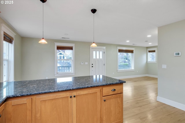 kitchen featuring pendant lighting, recessed lighting, dark stone counters, light wood finished floors, and baseboards