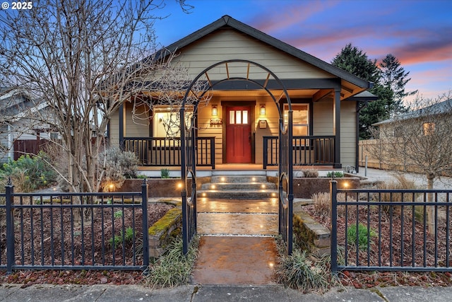 bungalow featuring a porch and a fenced front yard