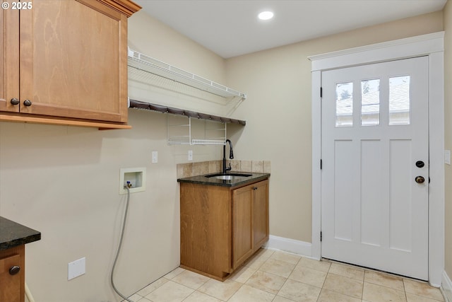 laundry area featuring baseboards, washer hookup, light tile patterned floors, cabinet space, and a sink