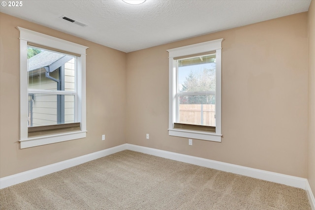 carpeted spare room with visible vents, a textured ceiling, and baseboards