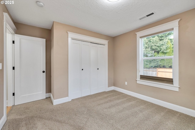 unfurnished bedroom with visible vents, baseboards, carpet floors, a closet, and a textured ceiling