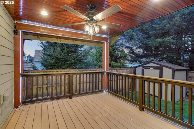 wooden deck featuring an outbuilding, a fenced backyard, a storage shed, and a ceiling fan