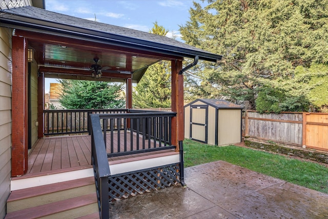 deck featuring a ceiling fan, a fenced backyard, an outdoor structure, a storage unit, and a patio