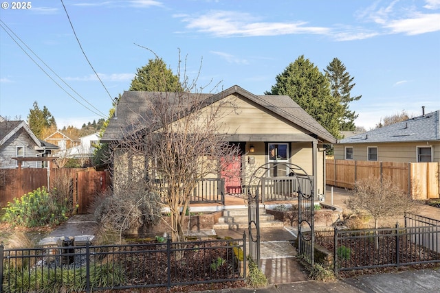 bungalow featuring a porch, fence private yard, and roof with shingles