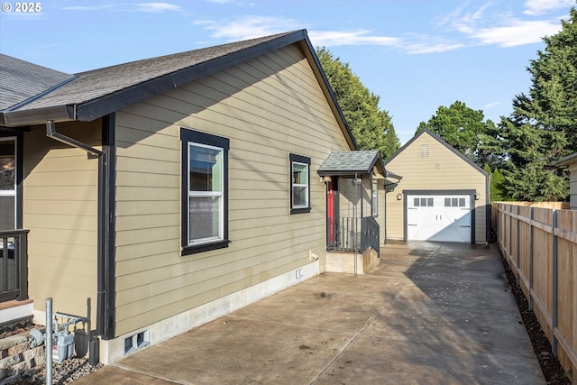 view of side of home featuring an outbuilding, fence, driveway, and roof with shingles