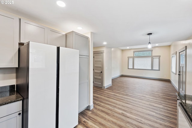 kitchen with gray cabinets, light hardwood / wood-style floors, decorative light fixtures, dark stone counters, and white fridge