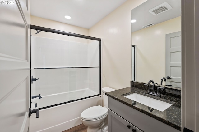 full bathroom featuring vanity, hardwood / wood-style floors, shower / bath combination with glass door, and toilet