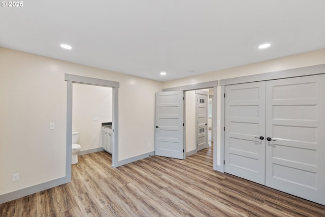 unfurnished bedroom with light hardwood / wood-style flooring, a closet, and ensuite bathroom