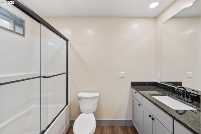 full bathroom featuring wood-type flooring, vanity, shower / bath combination with glass door, and toilet