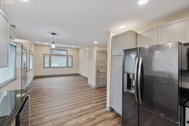 kitchen featuring appliances with stainless steel finishes, pendant lighting, gray cabinetry, dark stone counters, and light wood-type flooring