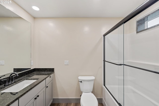 full bathroom with vanity, combined bath / shower with glass door, hardwood / wood-style floors, and toilet