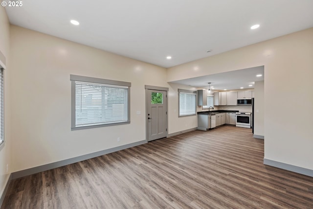 kitchen featuring white cabinetry, wood-type flooring, sink, stainless steel range, and plenty of natural light