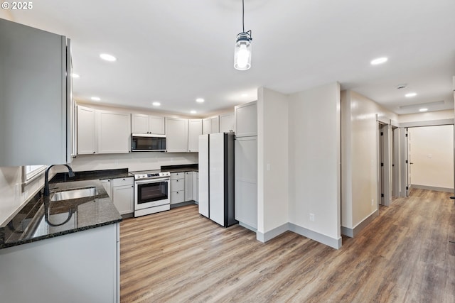 kitchen with pendant lighting, sink, white cabinetry, stainless steel appliances, and light hardwood / wood-style floors