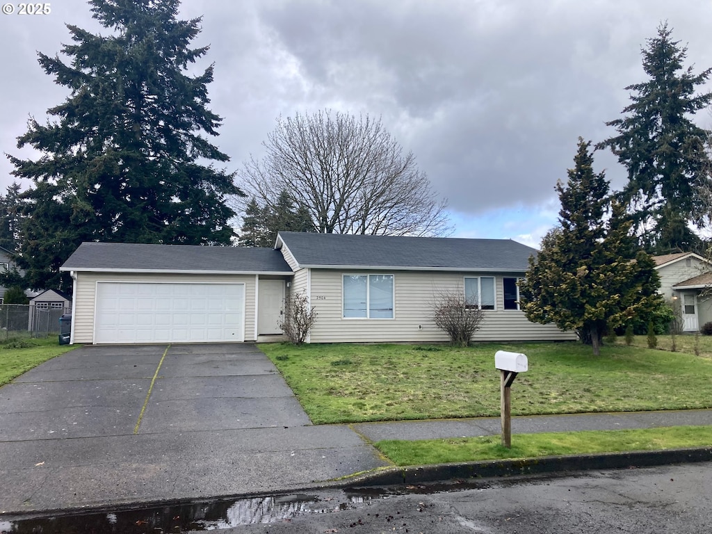 ranch-style house featuring a front lawn, concrete driveway, and a garage