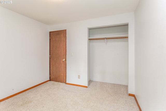 unfurnished bedroom featuring carpet floors, baseboards, and a closet
