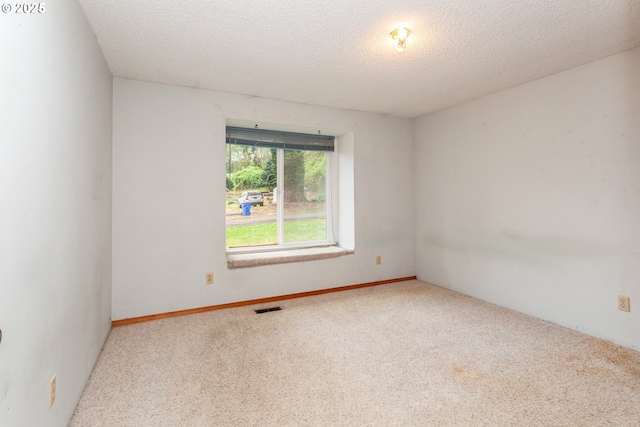 spare room featuring visible vents, a textured ceiling, and carpet