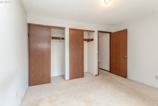 unfurnished bedroom with multiple closets, carpet flooring, and a textured ceiling