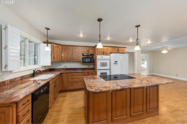 kitchen with black appliances, brown cabinetry, a sink, and light wood finished floors