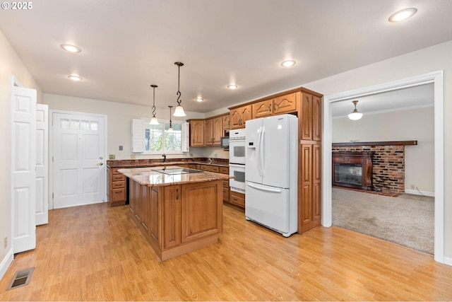 kitchen featuring light wood-style floors, a brick fireplace, white appliances, and visible vents