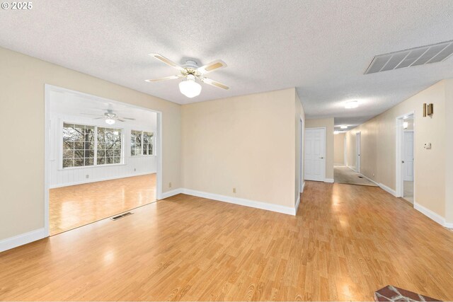 unfurnished living room featuring light wood-type flooring, visible vents, and a textured ceiling