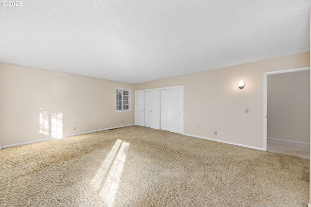 interior space with a textured ceiling, carpet, and baseboards