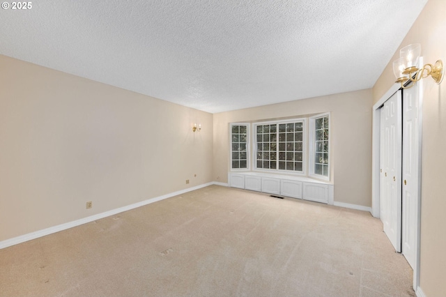 interior space featuring carpet, a textured ceiling, and baseboards