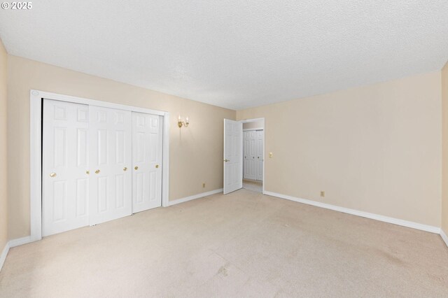 unfurnished bedroom featuring light carpet, a textured ceiling, and baseboards