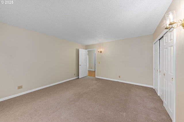 unfurnished bedroom with a textured ceiling, a closet, baseboards, and carpet flooring