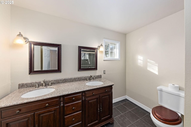 bathroom featuring toilet, tile patterned flooring, double vanity, and a sink