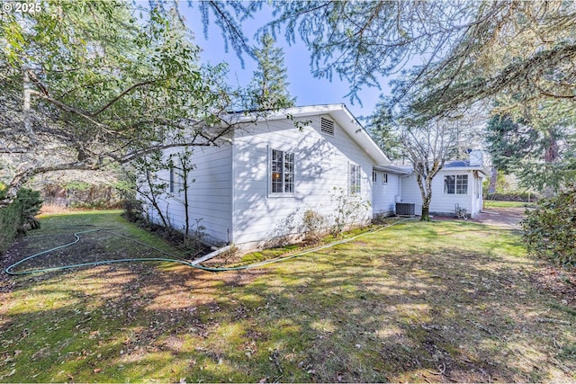 view of side of home featuring a yard and central AC unit