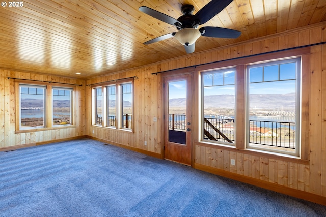 unfurnished sunroom featuring ceiling fan, wooden ceiling, and a mountain view