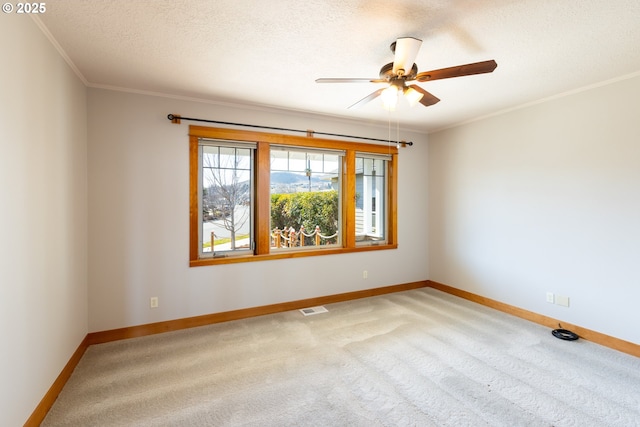 carpeted spare room with ornamental molding, visible vents, a textured ceiling, and baseboards