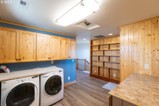 washroom with cabinet space, visible vents, wood finished floors, and washing machine and clothes dryer