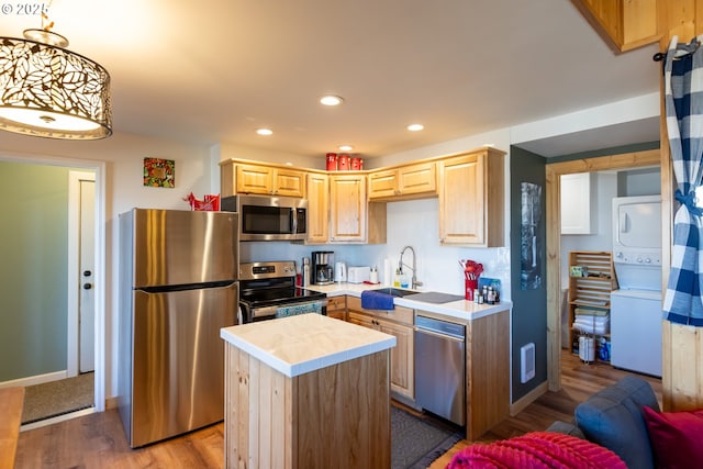 371 Summit Ridge Dr, The Dalles, OR 97058 - kitchen with appliances with stainless steel finishes, stacked washing machine and dryer, a sink, wood finished floors, and light brown cabinetry