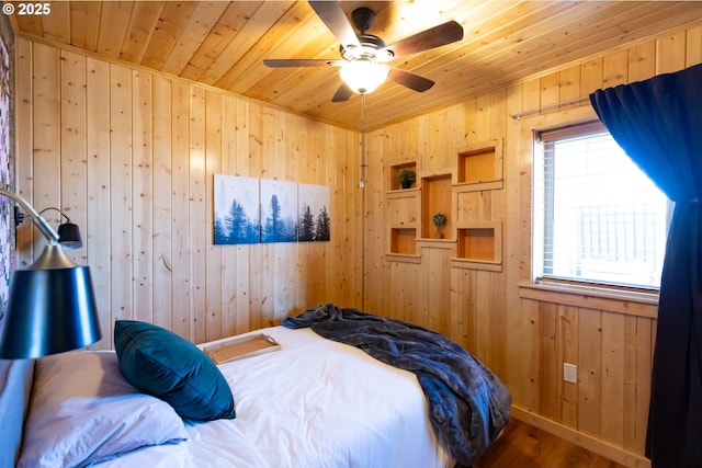 bedroom with wooden ceiling, wood walls, baseboards, and wood finished floors