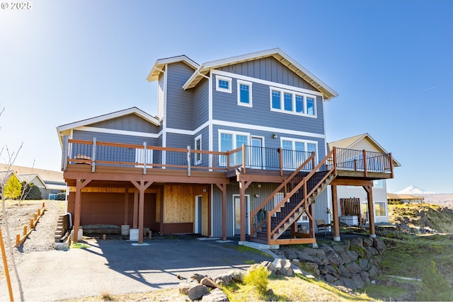 view of front of property featuring a deck, stairway, board and batten siding, and a patio area