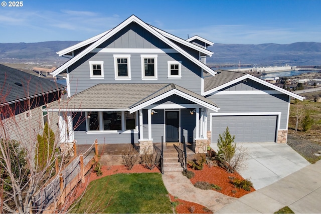 view of front of house with roof with shingles, concrete driveway, board and batten siding, a mountain view, and a garage