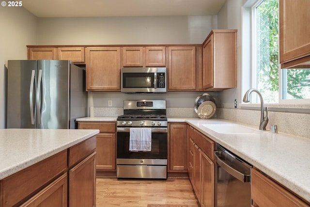 kitchen featuring a healthy amount of sunlight, appliances with stainless steel finishes, sink, and light hardwood / wood-style flooring