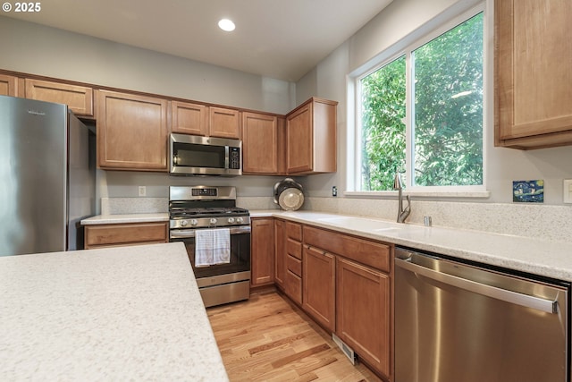 kitchen with appliances with stainless steel finishes, light hardwood / wood-style floors, and sink